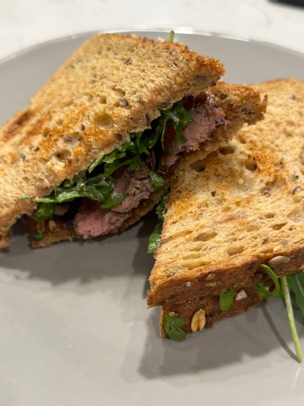 Steak sandwich with arugula and dijon mayo.